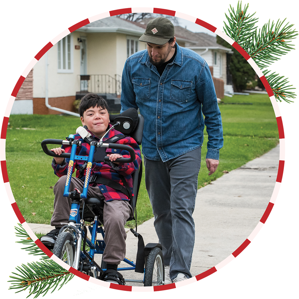 Thom riding bicycle outside with his dad walking behind